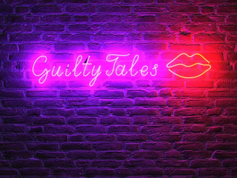 The Guilty Tales neon sign glowing on a brick wall